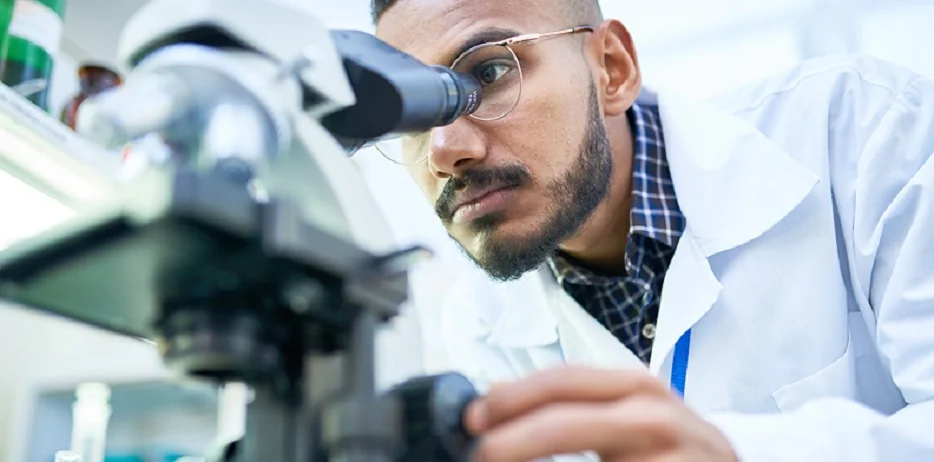 Researchers examining samples under a microscope in a laboratory